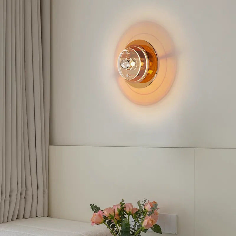 Wall-mounted light fixture on a neutral wall with a vase of flowers on a windowsill.